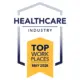Award badge: Healthcare Industry Top Workplaces May 2026, featuring a yellow ribbon/banner with dark blue text and a blue framed arch motif.