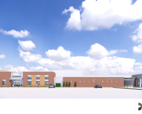 Wide view of a modern medical campus with brick and white buildings, a parking lot, and blue-sky backdrop with scattered clouds.