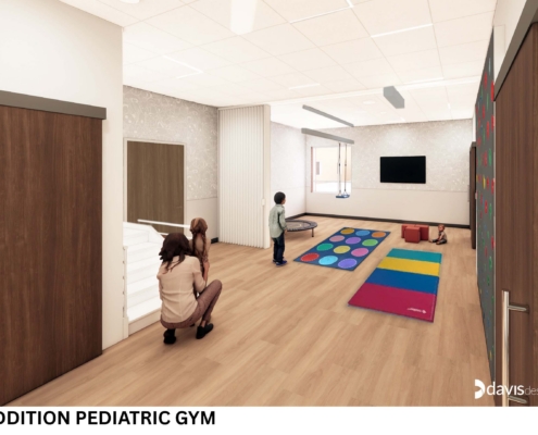 Children playing in a pediatric gym with colorful mats, foam blocks, and a small trampoline area in a bright room.