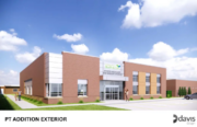 Exterior view of a modern brick medical building with a glass entrance and parking lot, under a blue sky.